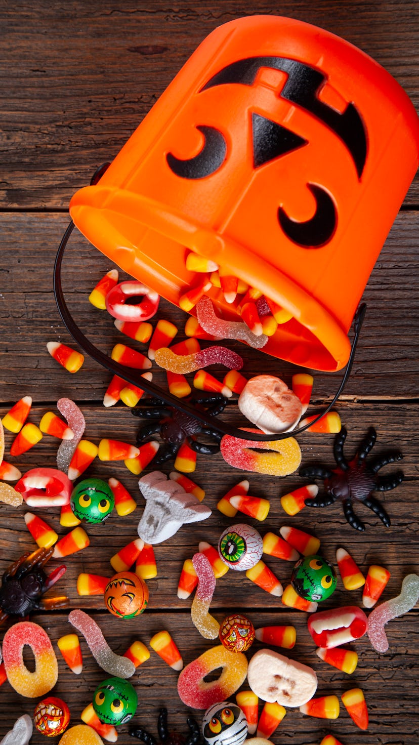 Halloween Jack o Lantern pail with bottom border of spilling candy over brown rustic wood