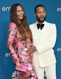 John Legend touching Chrissy Teigen's baby bump at the 2022 Emmy Awards. 