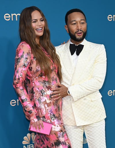 John Legend touching Chrissy Teigen's baby bump at the 2022 Emmy Awards. 