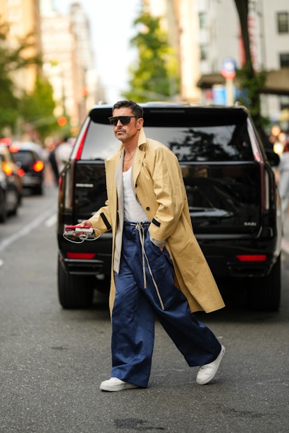 Alex Badia at New York Fashion Week in baggy pants and a trench coat.