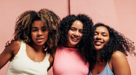 Three young women embrace during the September 2022 new moon in Libra, which will affect their zodia...