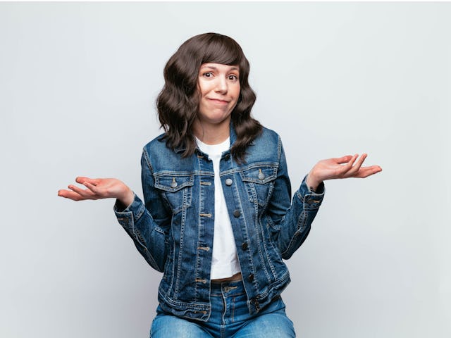 Studio photograph of Cute, young Latina woman wearing denim jacket, making a face. With medium lengt...