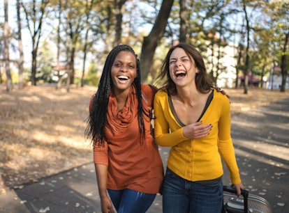 Two women share a laugh as they walk a nature trail during fall 2022, the most romantic season for t...