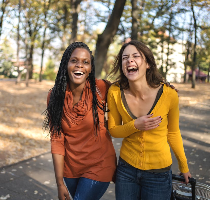 Two women share a laugh as they walk a nature trail during fall 2022, the most romantic season for t...