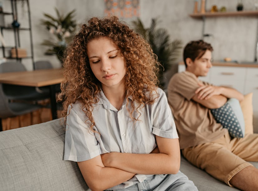 Young couple with relationship problems, sitting on the sofa in the living room and arguing.