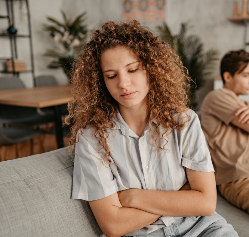 Young couple with relationship problems, sitting on the sofa in the living room and arguing.