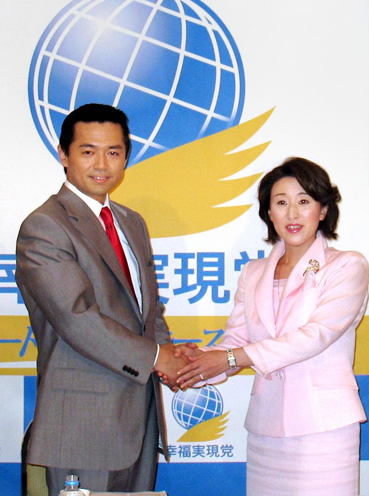 The Happiness Realization Party leader Jikido Aeba (L) shakes hands with Kyoko Okawa, wife of the fo...