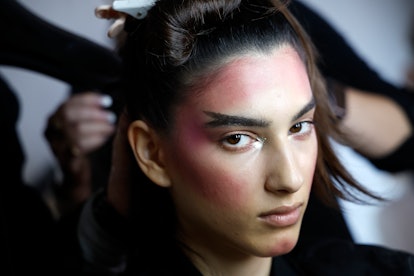 A model with grown-out brows prepares backstage during Christian Cowan fashion show during September...
