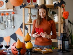 A woman looks at her phone to find DIY Halloween decorations from TikTok. 