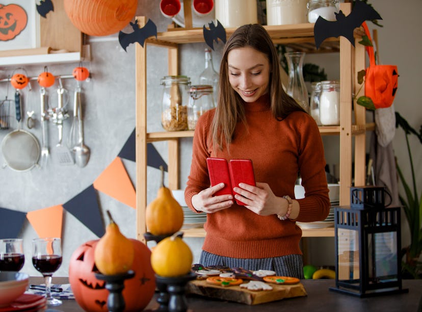 A woman looks at her phone to find DIY Halloween decorations from TikTok. 