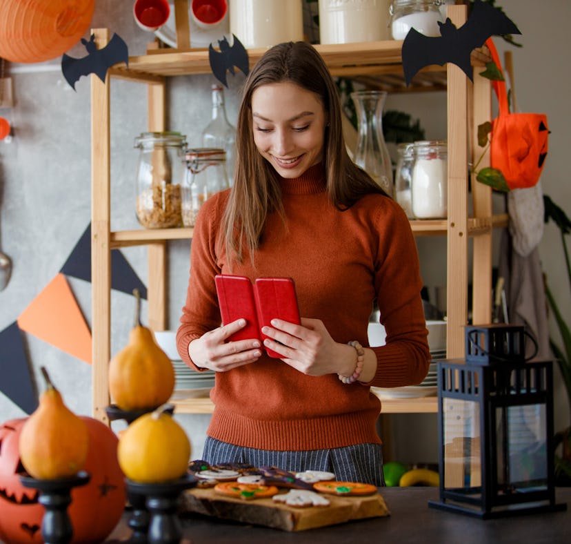 A woman looks at her phone to find DIY Halloween decorations from TikTok.