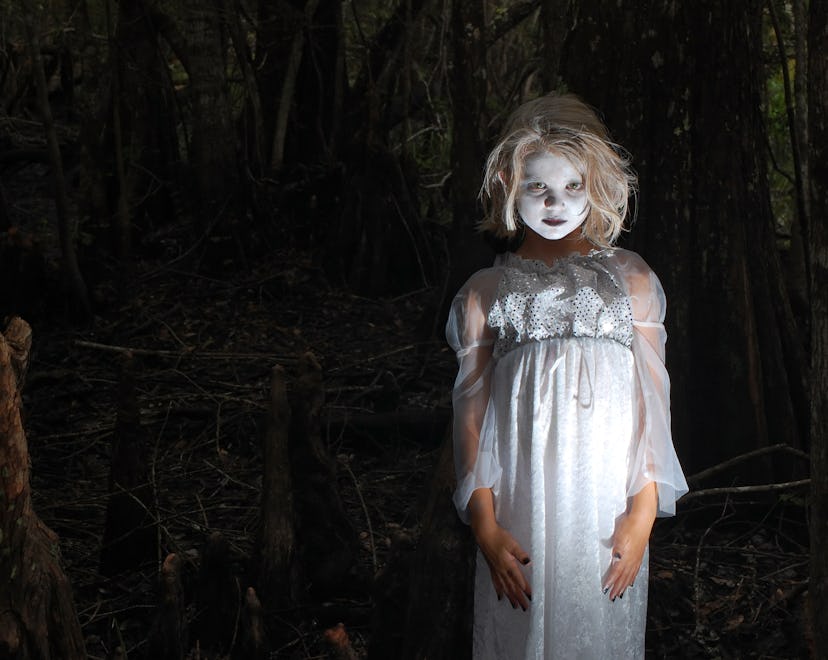 "A 7 year old little girl dressed up as a Ghoul or Ghost inside of a dark creepy cypress swamp, surr...