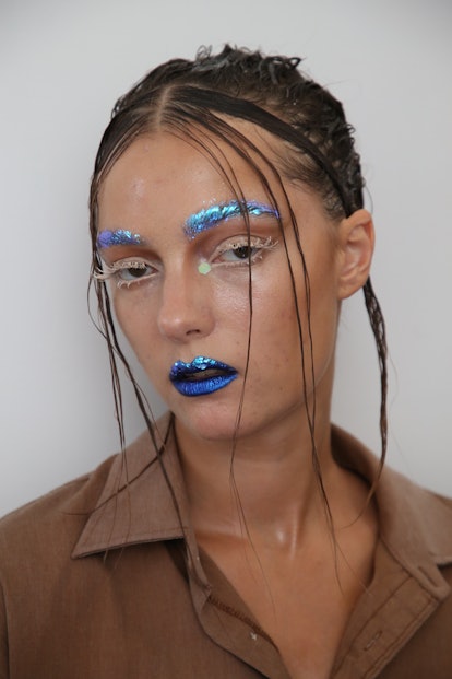 NYFW beauty trends include glitter brows and lips as seen on a model poses backstage at the Bach Mai...