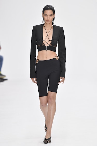 A model walking the runway in a black top and shorts during the Nensi Dojaka Ready to Wear Spring/Su...