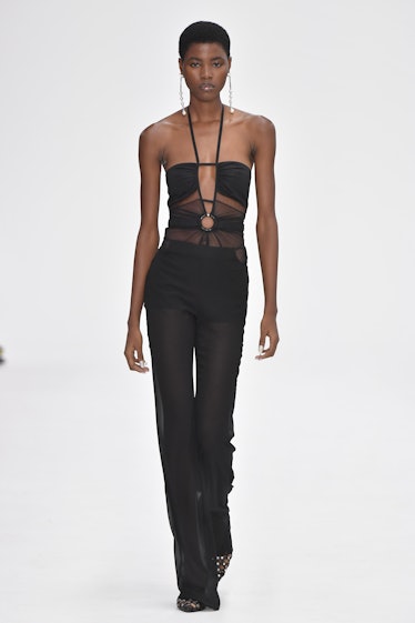 A model walking the runway in a black overall during the Nensi Dojaka Ready to Wear Spring/Summer 20...