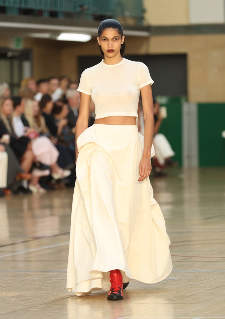 A model walking the runway in a white top and dress during the Molly Goddard show during London Fash...