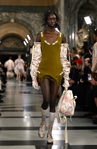 A model walking the runway in a green mini dress with white gloves during the Simone Rocha show duri...
