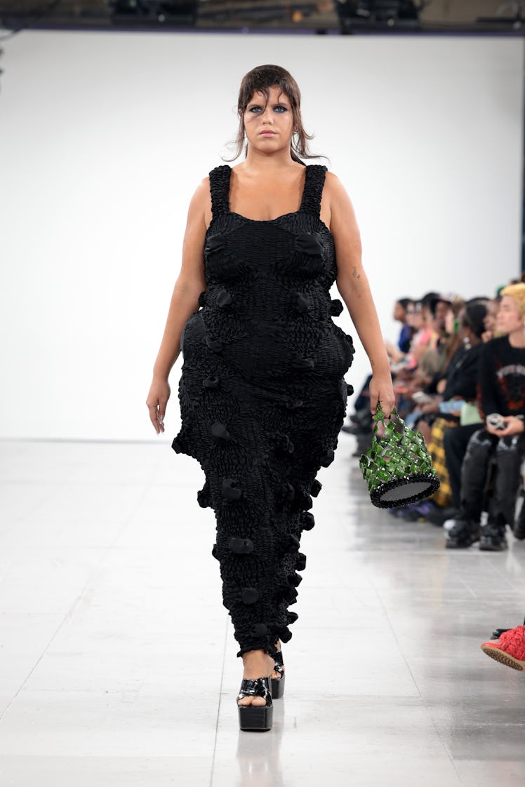 A model walking the runway in a black dress at the Feben show during London Fashion Week 
