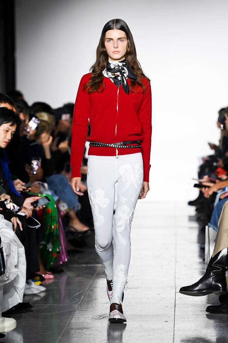 A model walking the runway in a red tracksuit top and white pants during the Stefan Cooke show durin...