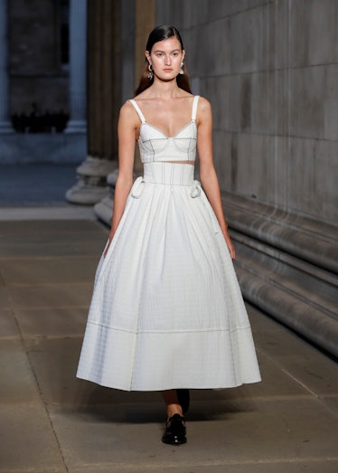 A model walking the runway while wearing a white dress at the Erdem show during London Fashion Week 