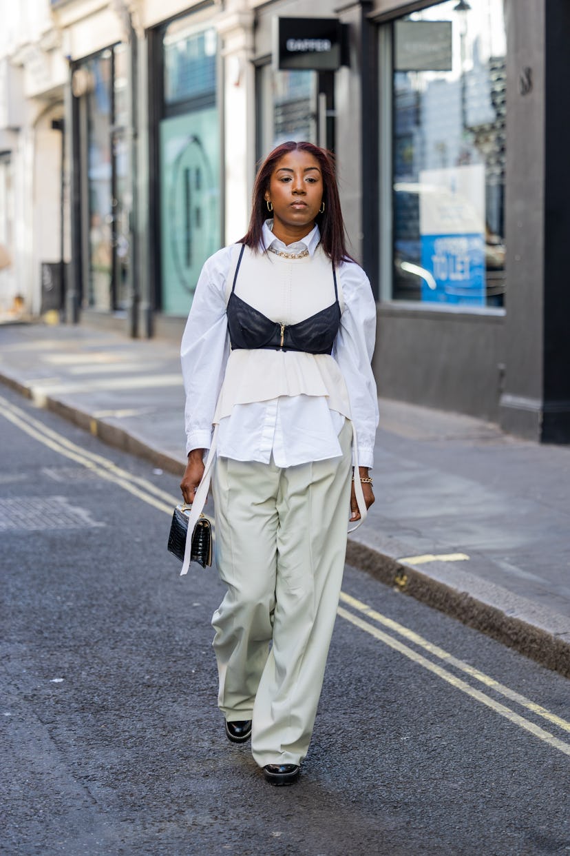 A guest wears white button shirt, beige pants, black bustier outside Eudon Choi during London Fashio...