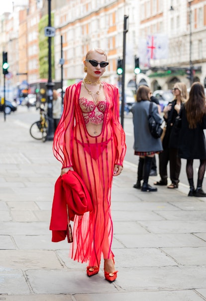 A guest wears red laced see through dress outside Poster Girl during London Fashion Week .