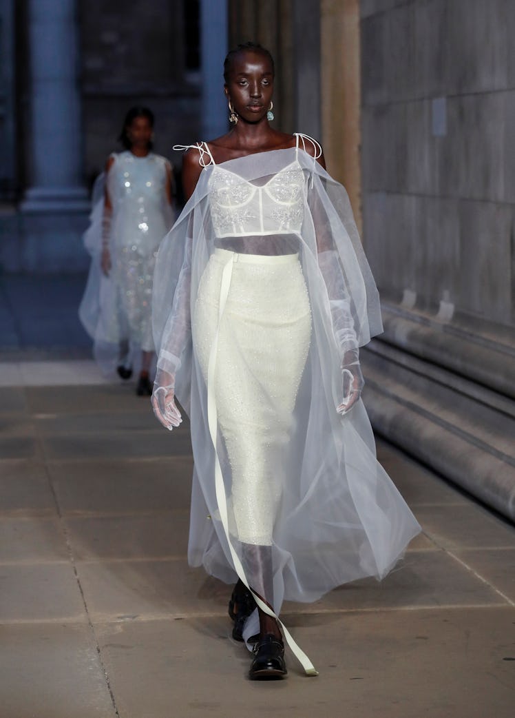 A model walking the runway in a white see-through gown at the Erdem show during London Fashion Week 