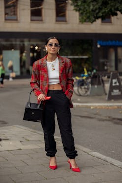 STOCKHOLM, SWEDEN - AUGUST 31:  A guest wearing black cargo pants, white crop top, red jacket, red s...