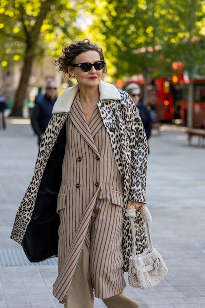 LONDON, UK - SEPTEMBER 17: Guests wear coats with animal prints, striped coats and teddy bag outsid.