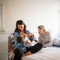 Family moments. Grandmother, mother and baby boy on bed at home, they are playing with baby boy. A R...