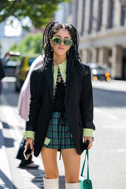 LONDON, UK - SEPTEMBER 17: Guests wear green checkered skirts and black blazers outside Marsha Popo.