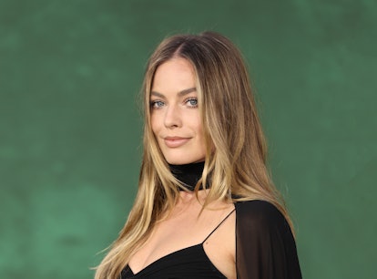 Margot Robbie, wearing a black dress against a green backdrop, stars in the upcoming 'Barbie' movie.
