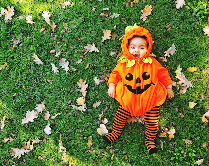 a baby dressed as a pumpkin in a round up for the best baby halloween costumes