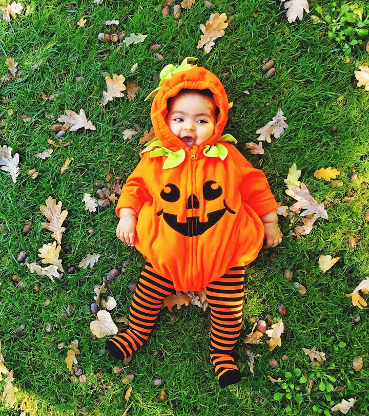 a baby dressed as a pumpkin in a round up for the best baby halloween costumes