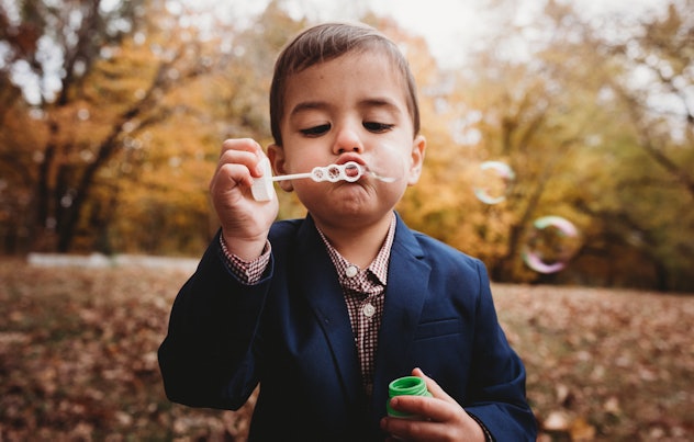 Adorable 3 Year Old boy blows bubbles in a formal outfit in the fall. bridgerton baby names