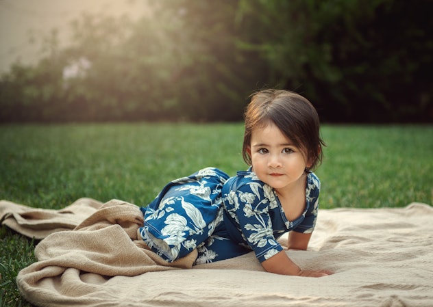 A pretty one year old girl looking at camera with her beautiful brown eyes. She is on a blanket in h...