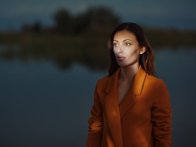 Young woman in an orange blazer at night in October 2022, the worst month for her zodiac sign.