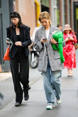 MILAN, ITALY - SEPTEMBER 21: A model (L) wears black sunglasses, a black blazer jacket, black suit p...