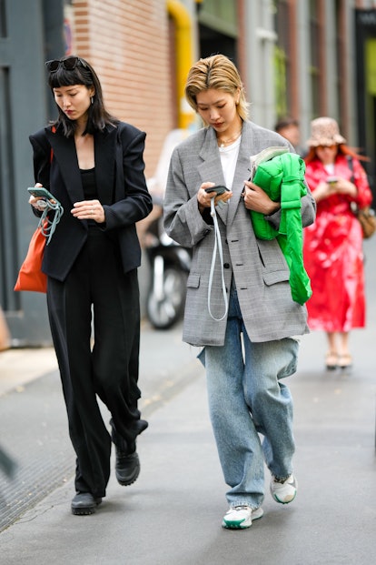 MILAN, ITALY - SEPTEMBER 21: A model (L) wears black sunglasses, a black blazer jacket, black suit p...