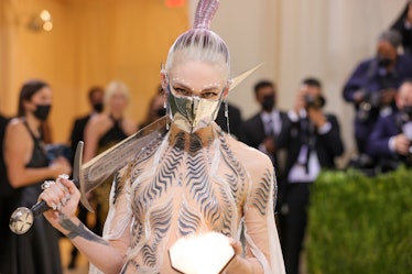 Grimes at the 2021 Met Gala; carrying a sword, a glowing orb and a metallic mask