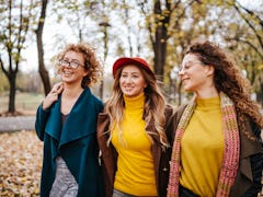 three women enjoy a walk in the park as they discuss the lucky signs that will have the best October...