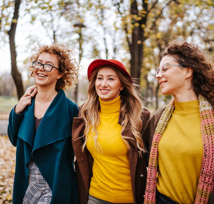 three women enjoy a walk in the park as they discuss the lucky signs that will have the best October...