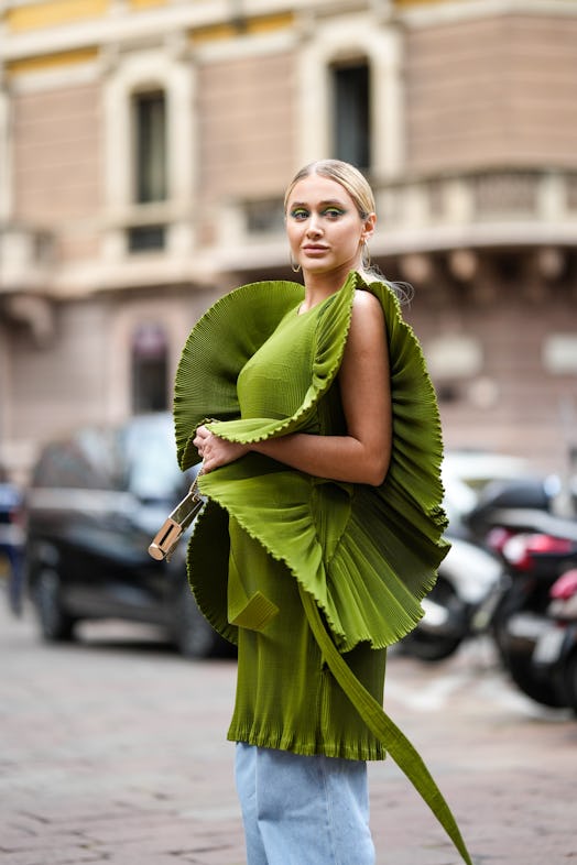 MILAN, ITALY - SEPTEMBER 21: A guest wears a khaki green short dress with oversized accordion wavy s...