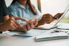 A couple sits at a table and tabulates their student loans