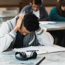 The student grabs his head in frustration after trying to think of a paper topic.