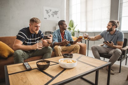 Diverse group of men watching soccer match on smart phone at home and cheering for favorite team.