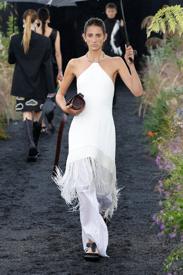 A model wearing a white fringed dress and pants from Jil Sander's Spring/Summer 2023 collection