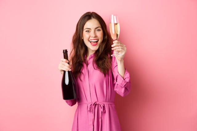 Celebration and holidays concept. Beautiful woman saying toast, raising glass of champagne and holdi...