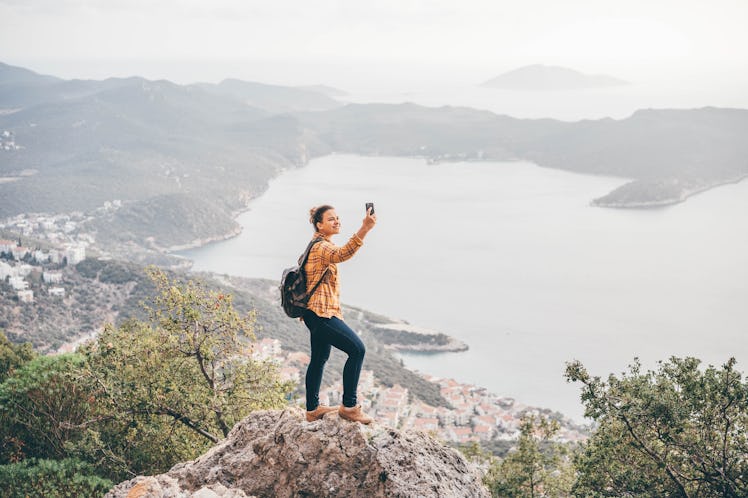 Woman enjoying the view and making selfie at the mountain, for which she needs a caption for mountai...
