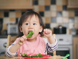 a baby eating broccoli in an article about baby led weaning, what is baby-led weaning, how to start,...